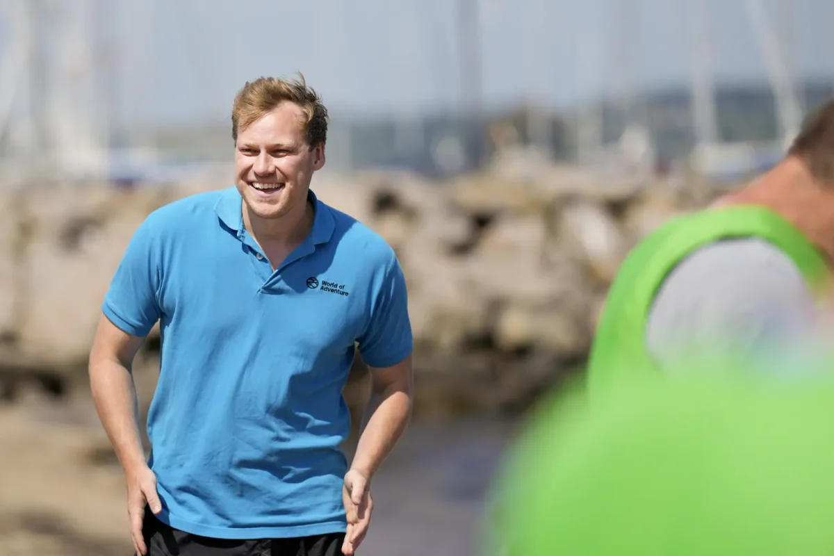 mand smiler ved havn med groen vest i baggrunden