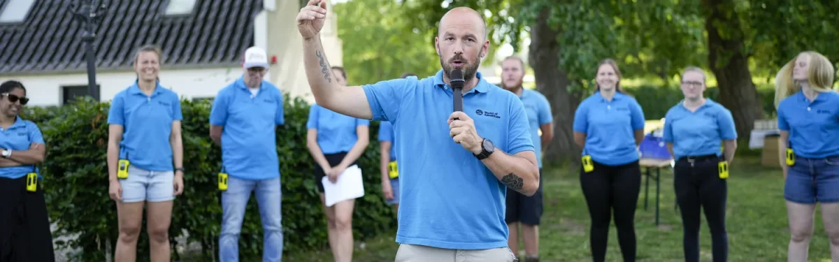 skaldet mand taler og peger op foran slotsbygning