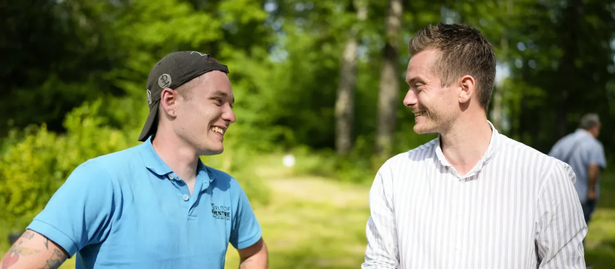 mand med tatoveringer taler med mand med tommestok