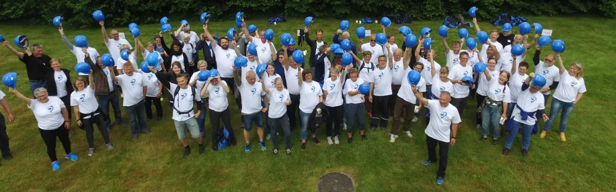 rejsegilde 2 stor gruppe loefter blaa sikkerhedshjelme i vejret
