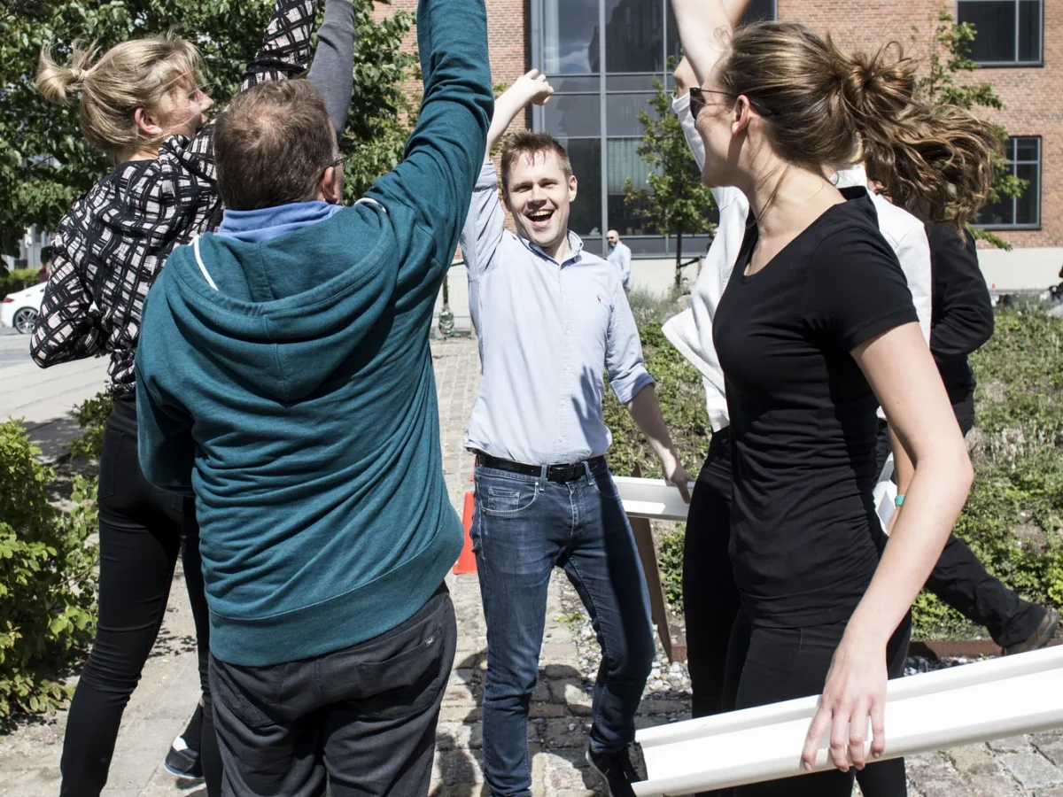 team (5) gruppe hopper og jubler med haenderne i vejret udendoers