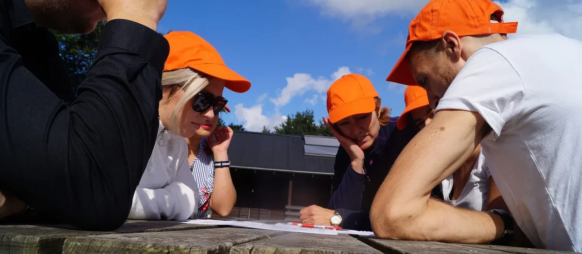 woa stemningsbillede 11 deltagere i orange kasketter studerer opgave ved bord