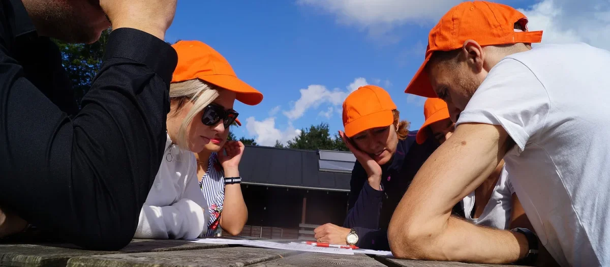 woa stemningsbillede 11 deltagere i orange kasketter studerer opgave ved bord