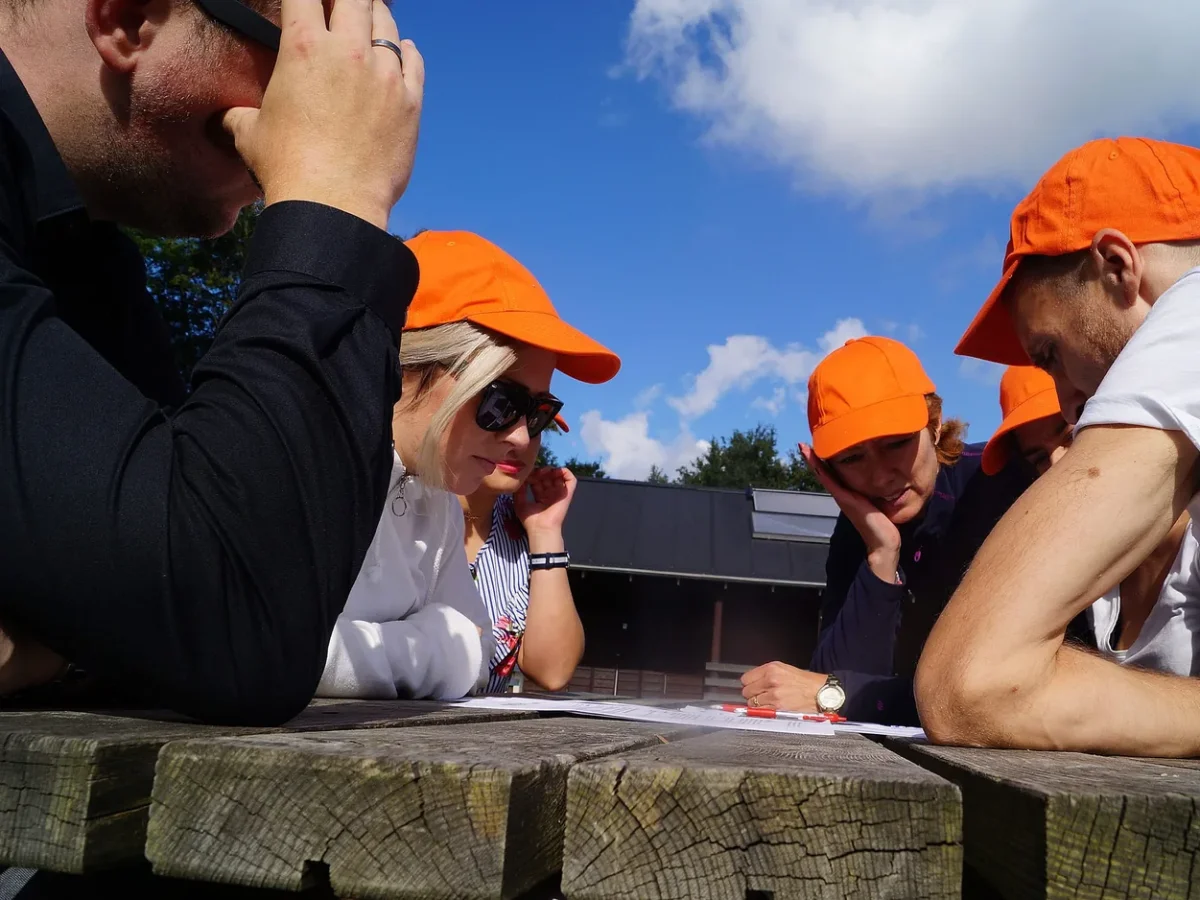 woa stemningsbillede 11 deltagere i orange kasketter studerer opgave ved bord