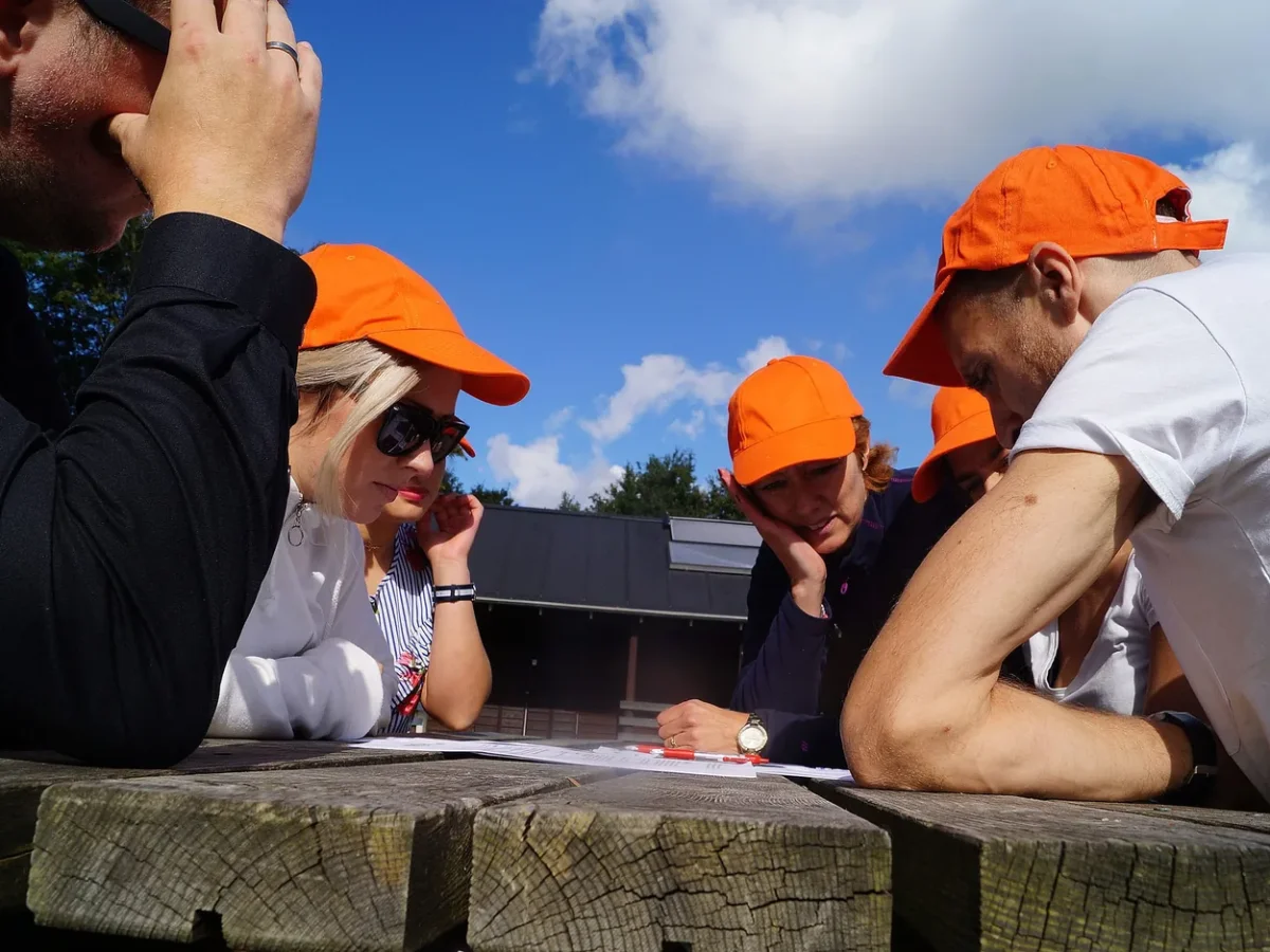 woa stemningsbillede 11 deltagere i orange kasketter studerer opgave ved bord
