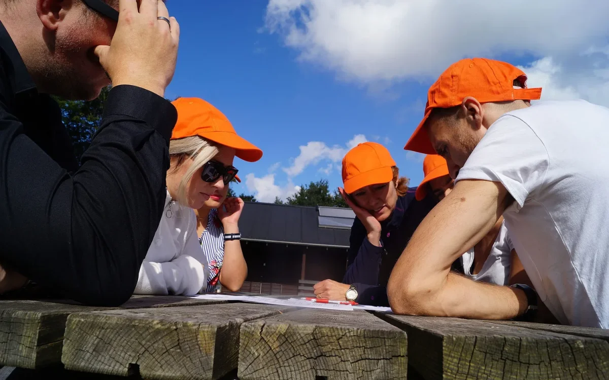 woa stemningsbillede 11 deltagere i orange kasketter studerer opgave ved bord