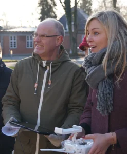 Gruppe deltagere til drone teambuilding holder fjernbetjeninger og ser koncentreret op i luften.