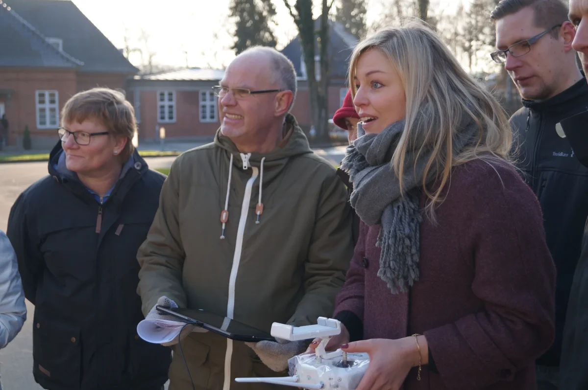 Gruppe deltagere til drone teambuilding holder fjernbetjeninger og ser koncentreret op i luften.