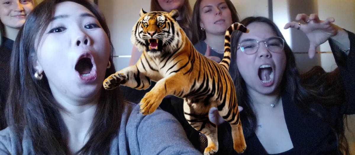 Gruppe af unge kvinder tager et sjovt billede med en digital tiger fra Fangerne på Fortet programmet.