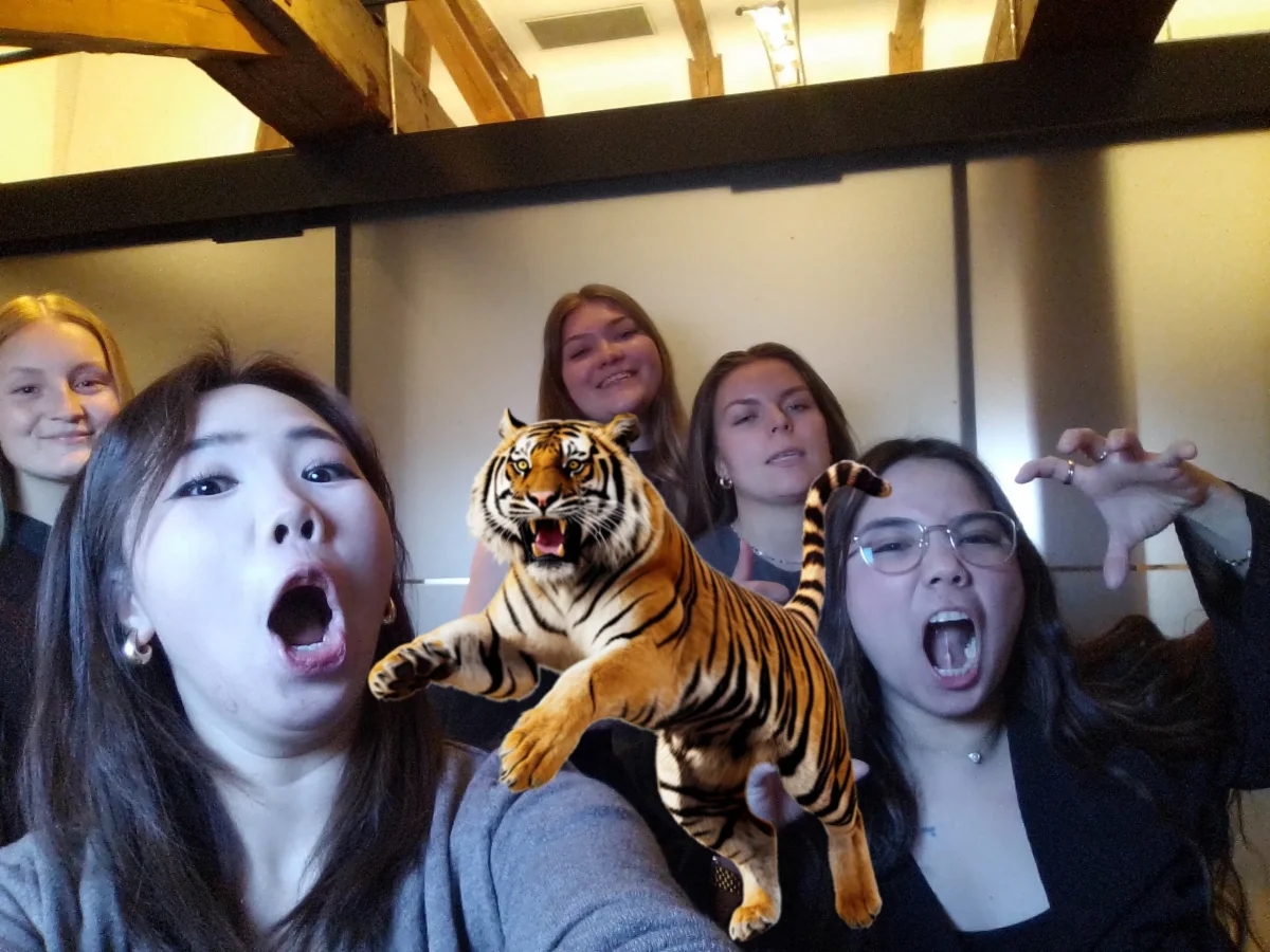 Gruppe af unge kvinder tager et sjovt billede med en digital tiger fra Fangerne på Fortet programmet.